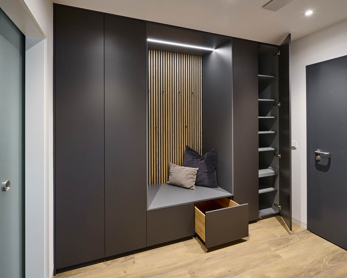Dunkler Schuh- und Jackenschrank als Garderobe im Flur mit Holzpaneelen und Sitzgelegenheit