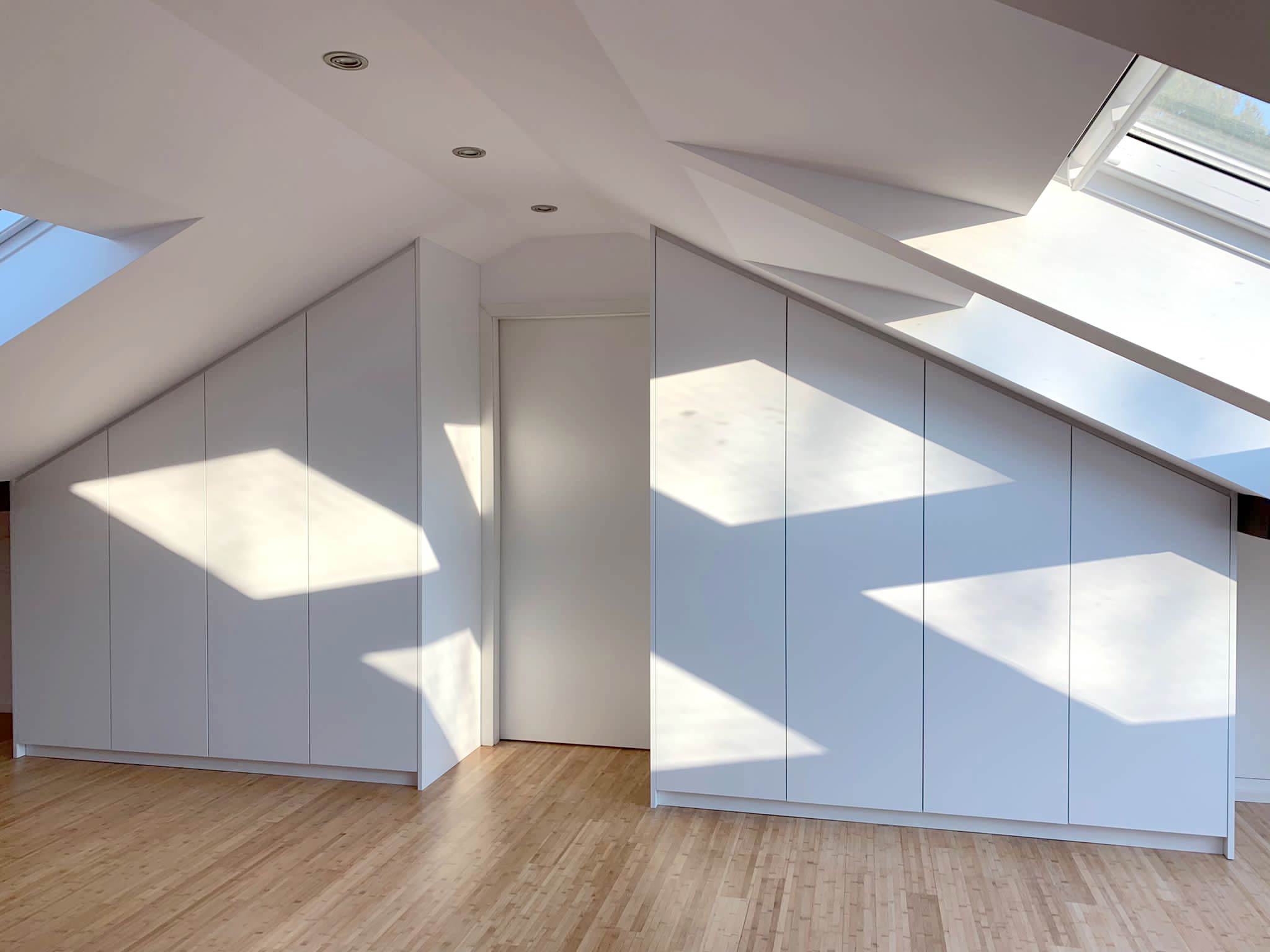 Zwei symmetrische, weiße Einbauschränke für Dachschräge, Eingangstür dazwischen